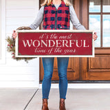 a woman holding a sign that says it's the most wonderful time of the