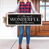 a woman holding a sign that says it's the most wonderful time of the