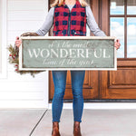 a woman holding a sign that says it's the most wonderful time of the