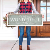 a woman holding a sign that says it's the most wonderful time of the