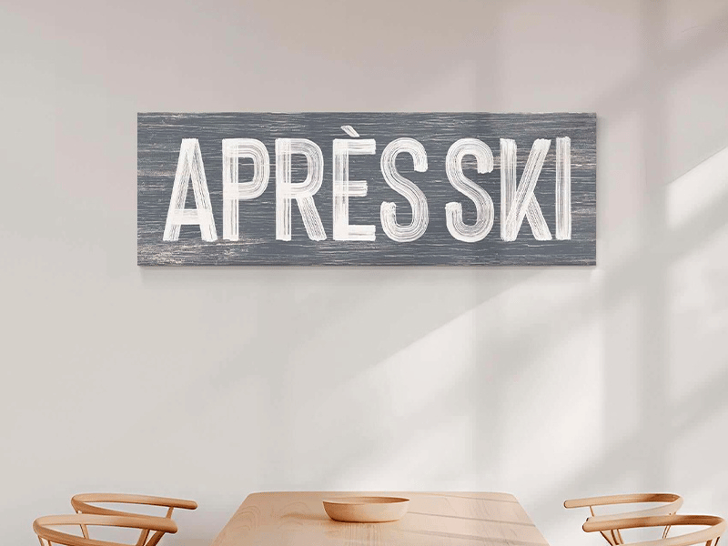 A cozy living room with a sofa and a large red "APRÈS SKI" sign on a wooden wall.