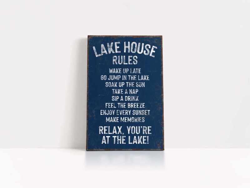 Blue rustic sign with "Lake House Rules" and relaxing activities listed in white text.