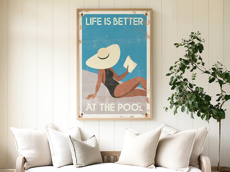 A cozy patio with a sofa, round table, and a pool-themed wall art that says "Life is better at the pool.