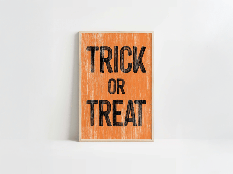 A framed orange sign with the words "TRICK OR TREAT" printed in large black letters.
