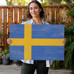 a woman holding a sign with the flag of sweden