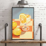 A framed painting depicting a glass of lemonade with lemon slices on a checkered tablecloth, set against a brick wall.