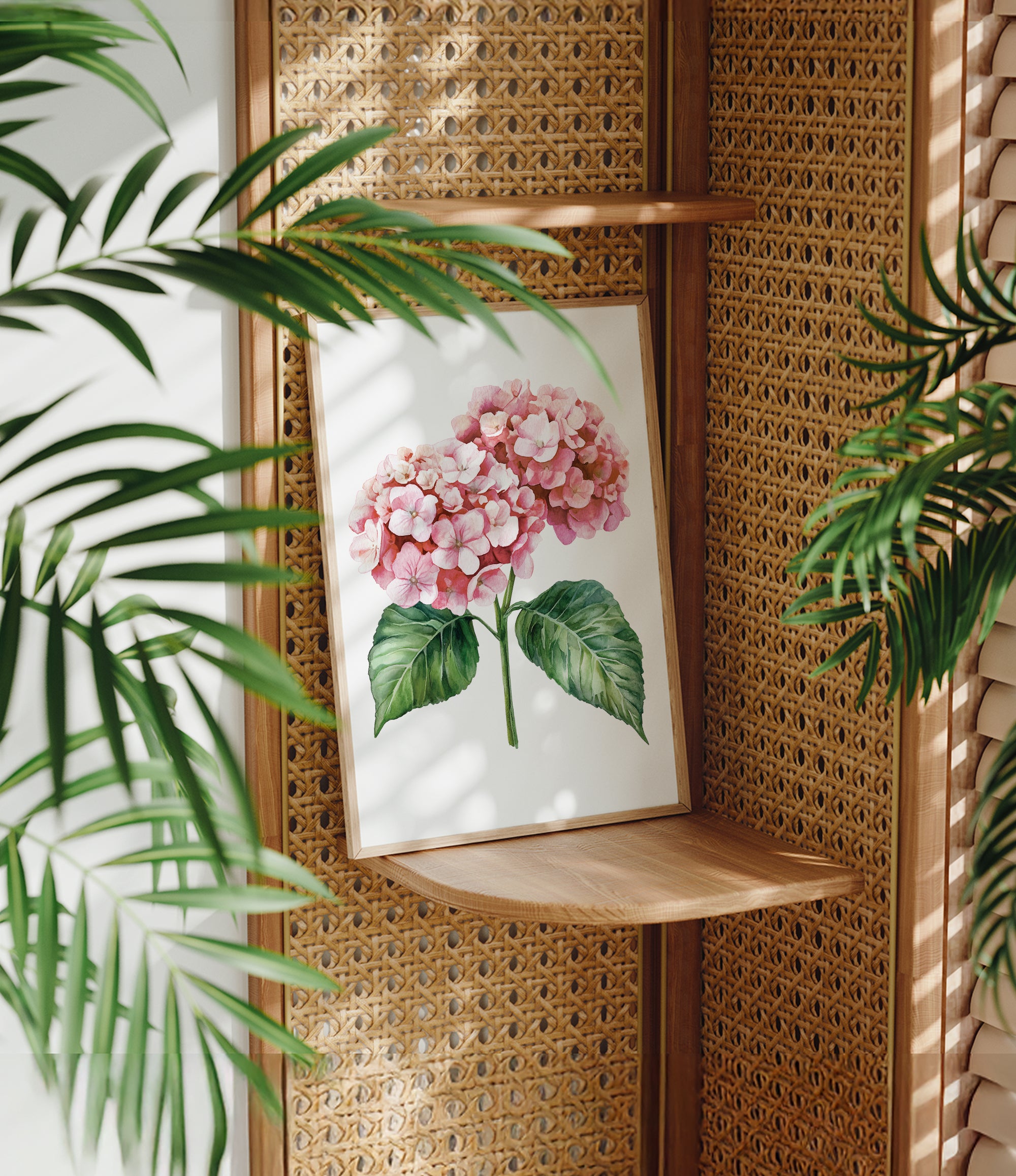 a framed painting of a pink hydrangea flower on a wooden shelf, surrounded by lush green leaves.