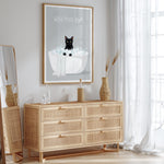 a wooden dresser with a framed poster of a cat sitting in a bathtub, accompanied by the text "WASH YOUR PAWS".