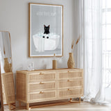 a wooden dresser with a framed poster of a cat sitting in a bathtub, accompanied by the text "WASH YOUR PAWS".