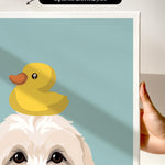 A hand is holding a framed print featuring a cartoon image of a duck sitting on a dog's head.