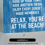The Beach House Rules Sign, crafted from painted wood in ocean blue, features bold white text—"Relax, you're at the beach!"—making it a cheerful addition to any coastal wall art or beach house decor.
