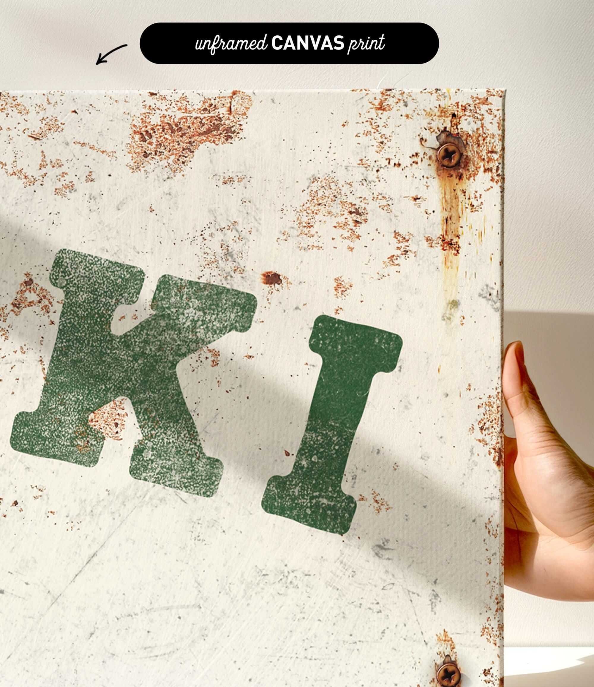 a close-up view of a white canvas print with a green and black text design. The text appears to be a stylized representation of the letters "K" and "I".