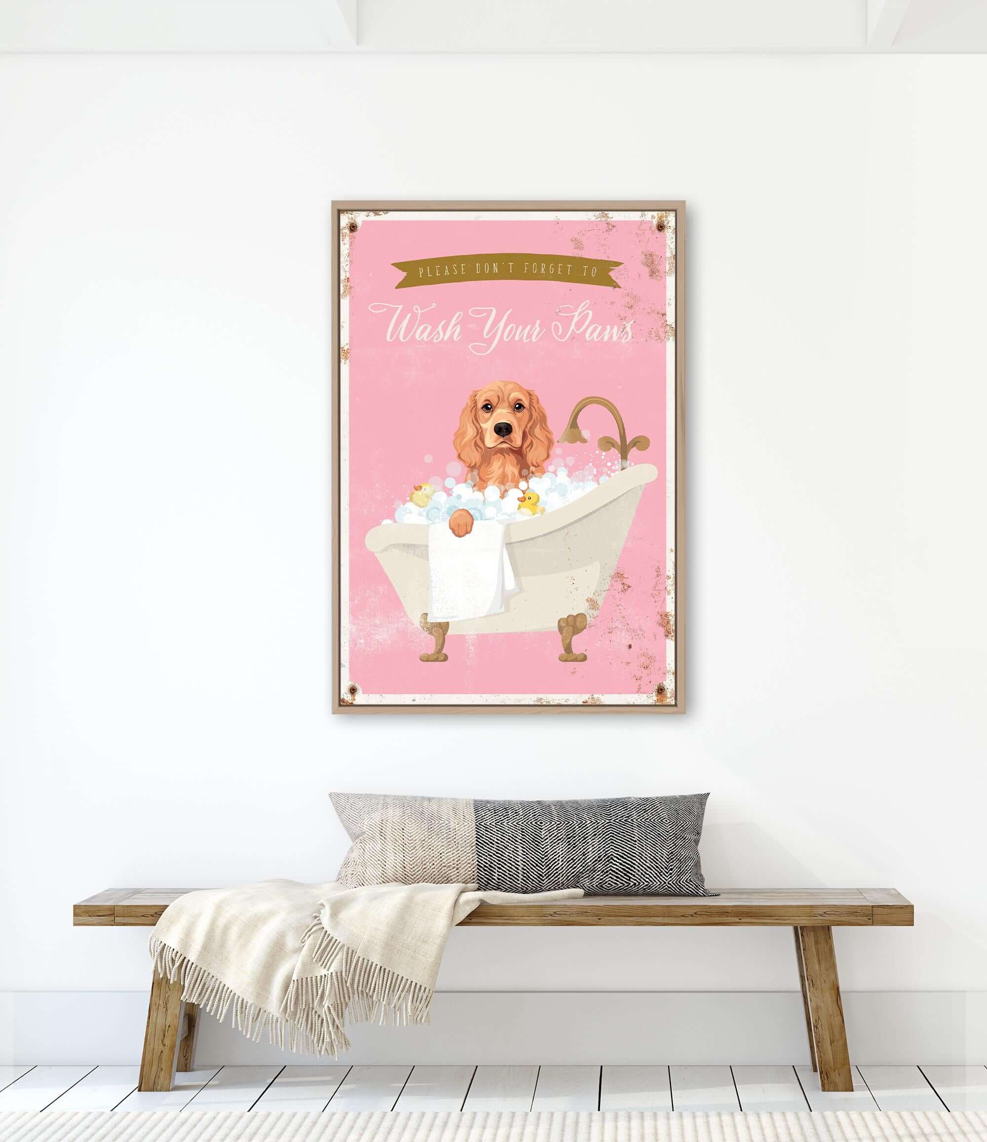 A framed poster with a dog sitting in a bathtub, surrounded by bubbles, is hanging on a white wall above a wooden bench.