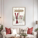 a cozy living room with a white sofa adorned with red and white plaid throw pillows. Above the sofa, there is a framed picture of a ski sign with the word "APRES" written on it. The room also includes a coffee table with a tray and a few decorative items, creating a warm and inviting atmosphere.
