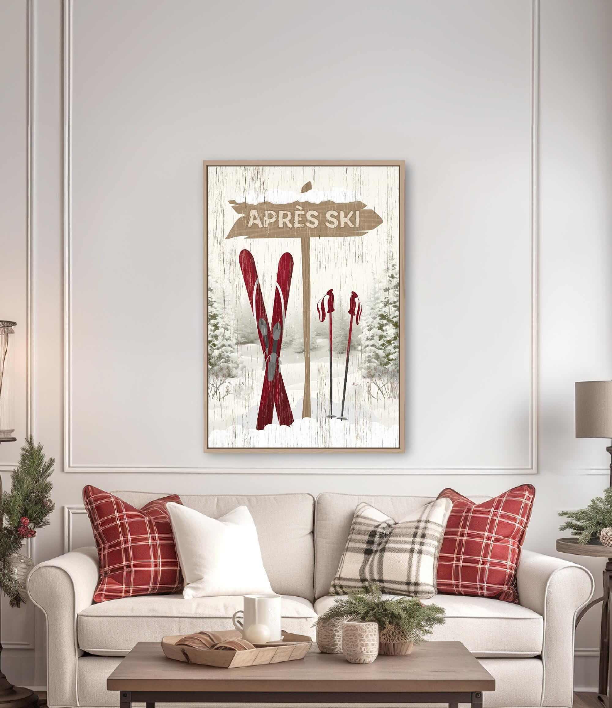 a cozy living room with a white sofa adorned with red and white plaid throw pillows. Above the sofa, there is a framed picture of a ski sign with the word "APRES" written on it. The room also includes a coffee table with a tray and a few decorative items, creating a warm and inviting atmosphere.