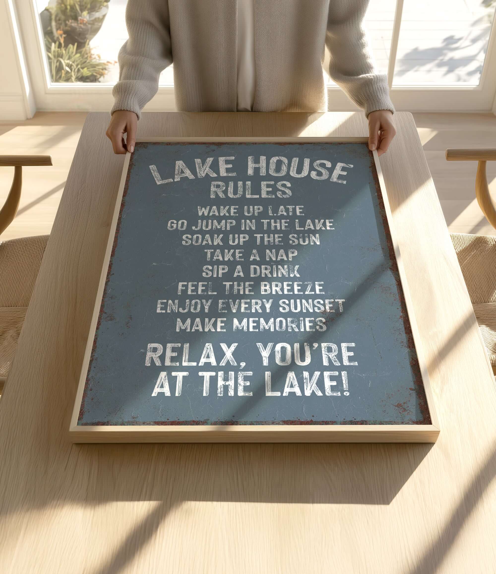 A person is holding up a sign that says "LAKESHOUSE RULES" in a wooden frame.