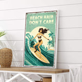 a framed poster with a woman surfing on a wave, along with the text "REACH HAIR DON'T CARE" written above the image.