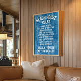 The Beach House Rules Sign, Painted Wood, Ocean Blue, adds charming coastal wall art to a cozy, sunlit living room with a tan couch and wooden walls.