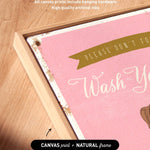 a pink canvas with the text "Please don't forget to wash your hands" written on it. The canvas is framed in a natural frame, and there is a small arrow pointing to the bottom right corner of the canvas.