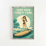 The image is a framed poster with a vintage-style illustration of a woman paddleboarding on a lake. The poster features the text "LAKESHAIR DON'T CARE" prominently displayed.