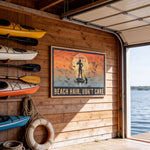 a wooden wall with a framed poster that says "BEACH HAIR, DON'T CARE" and a silhouette of a person paddleboarding. There are several kayaks and a life preserver hanging on the wall, and a garage door is visible in the background.