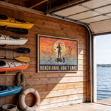 a wooden wall with a framed poster that says "BEACH HAIR, DON'T CARE" and a silhouette of a person paddleboarding. There are several kayaks and a life preserver hanging on the wall, and a garage door is visible in the background.