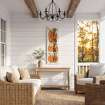 a cozy and inviting porch with a rustic charm, featuring a wicker sofa, a wooden table, and a decorative pumpkin sign. The porch is illuminated by a chandelier, and the scene is set against a backdrop of trees with autumn foliage.