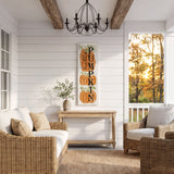 a cozy and inviting porch with a rustic charm, featuring a wicker sofa, a wooden table, and a decorative pumpkin sign. The porch is illuminated by a chandelier, and the scene is set against a backdrop of trees with autumn foliage.