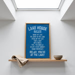 a framed sign with a blue background and white text, placed on a shelf above a bowl.