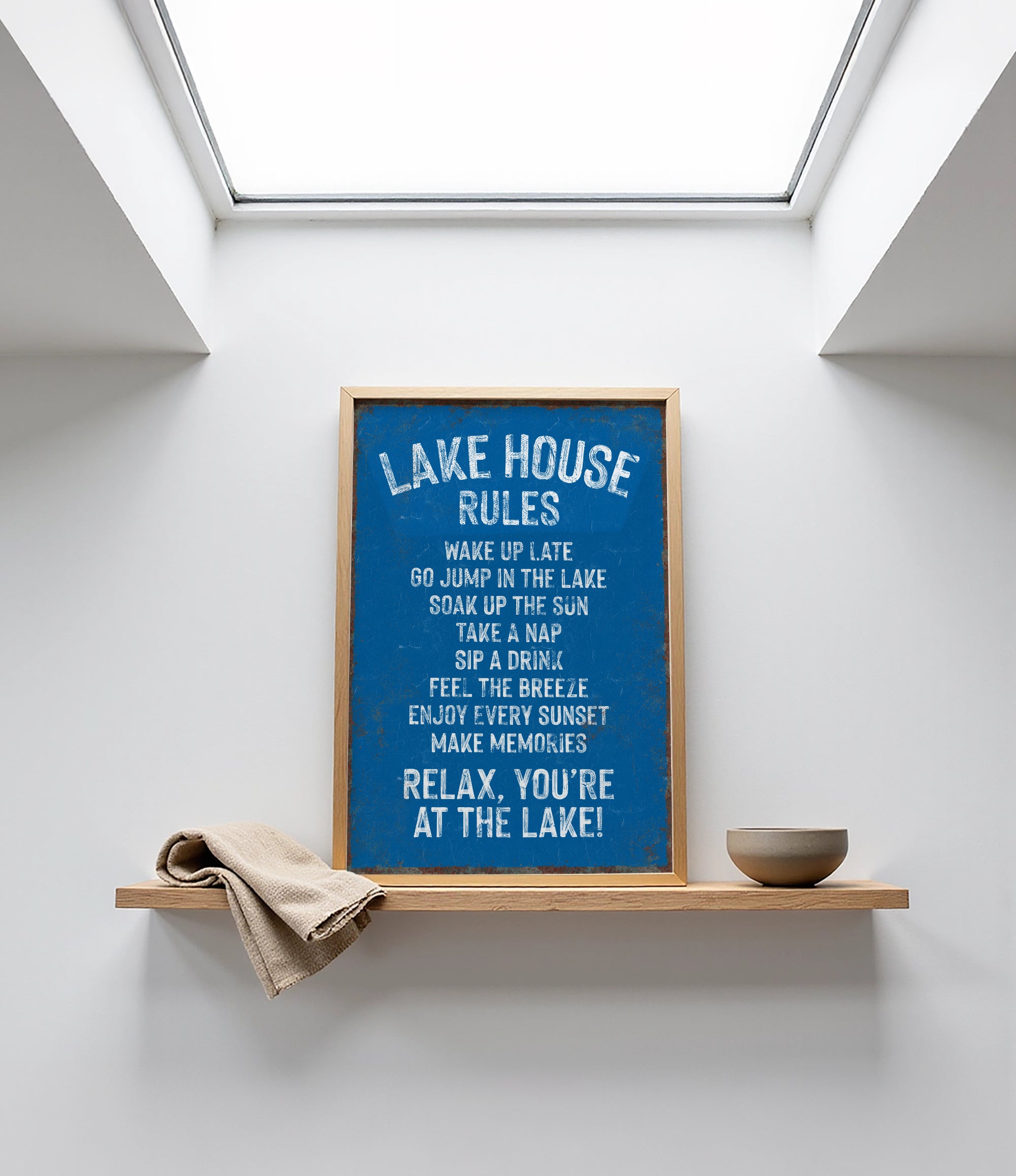 a framed sign with a blue background and white text, placed on a shelf above a bowl.