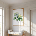 a white room with a large painting of a green hydrangea flower hanging on the wall. In front of the painting, there is a white bench with two white cushions. The room has white walls and a wooden floor, creating a clean and elegant atmosphere.
