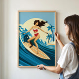 A woman is standing in front of a framed illustration of a woman surfing on a surfboard, with palm trees and a sunset in the background.
