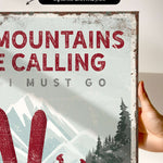 a hand holding a sign that says mountains are calling