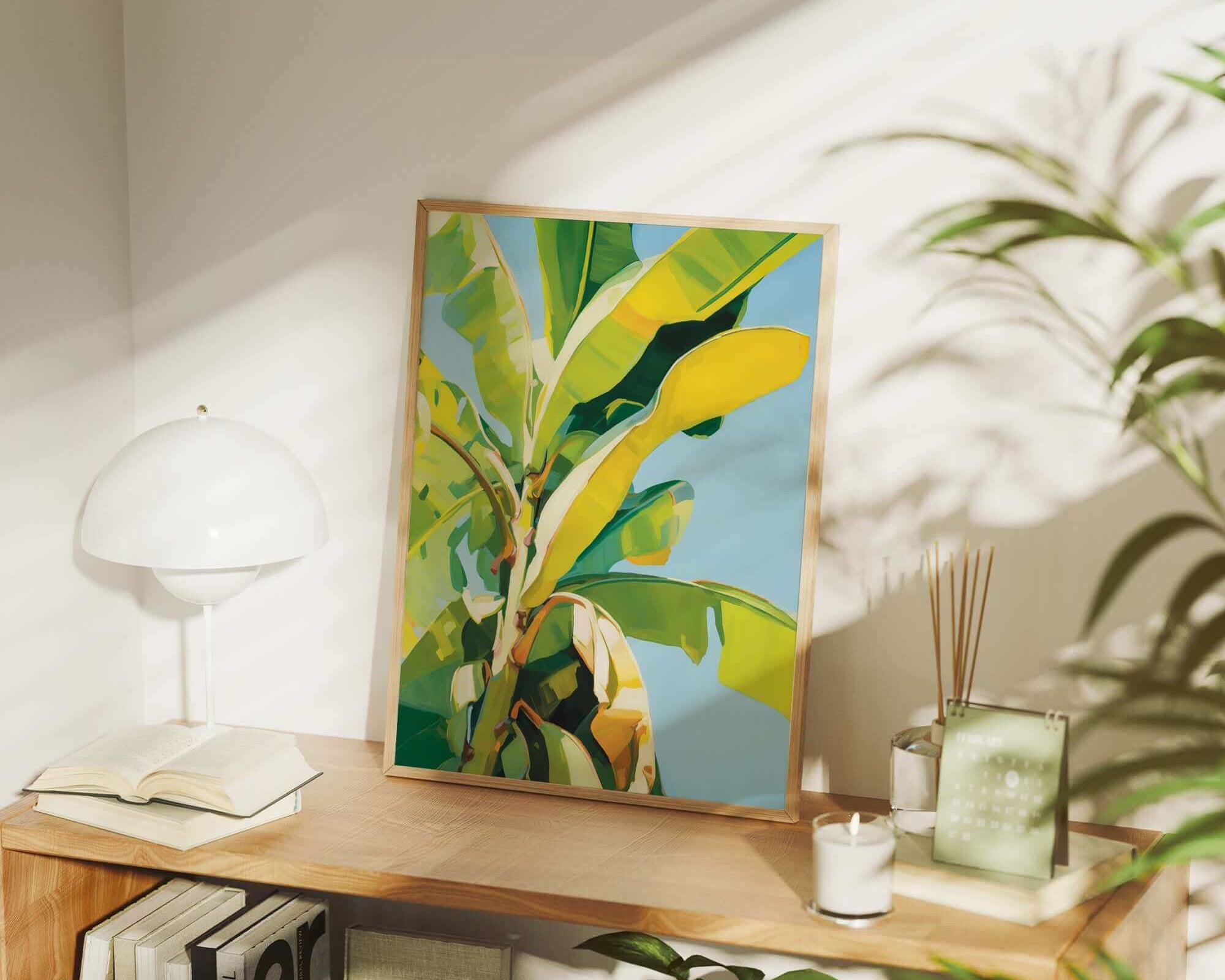 a wooden shelf with a framed painting of a banana tree, a lamp, and various books and plants.