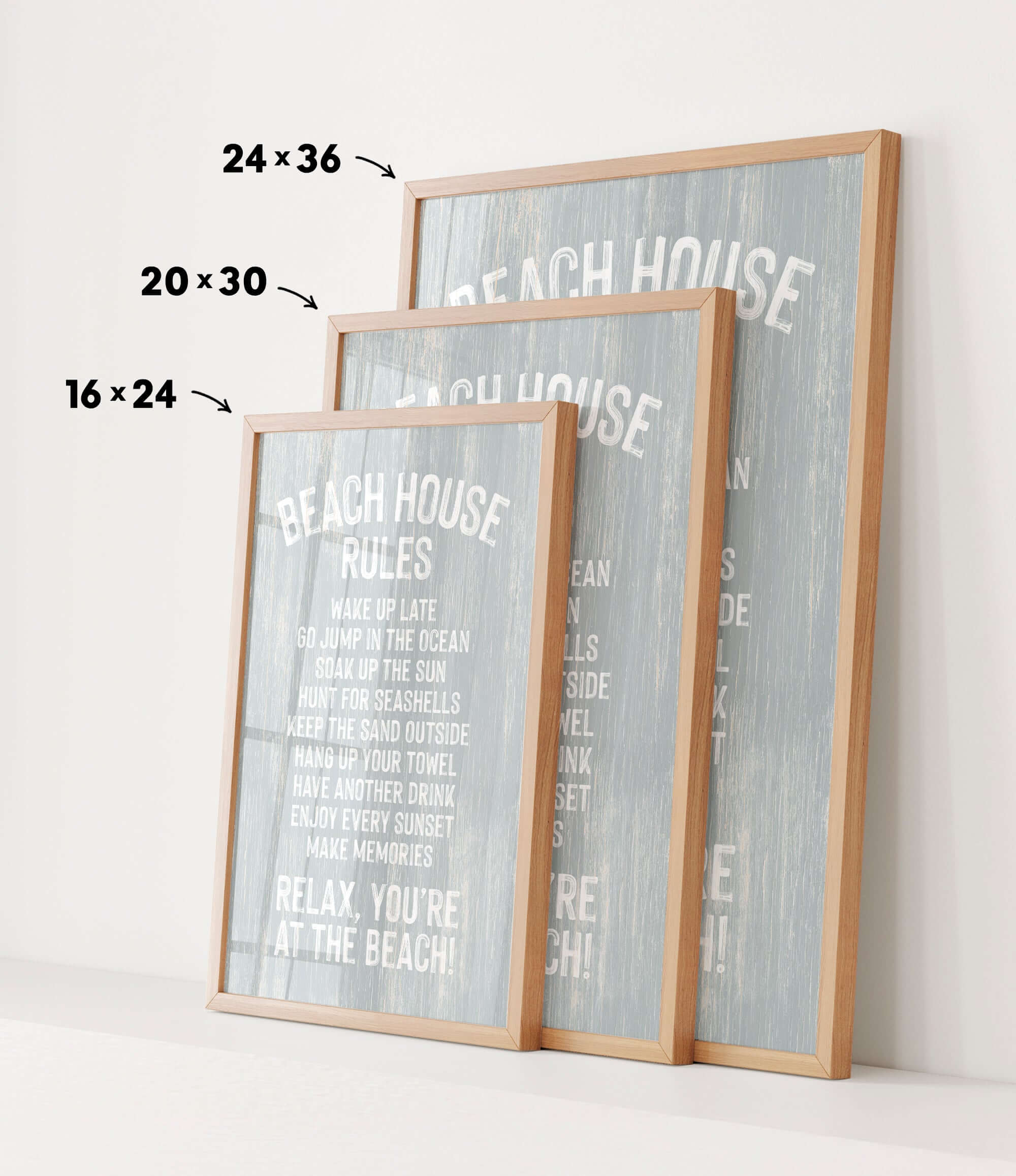 three framed beach house rules posters, each with a different size and orientation, displayed on a white wall.