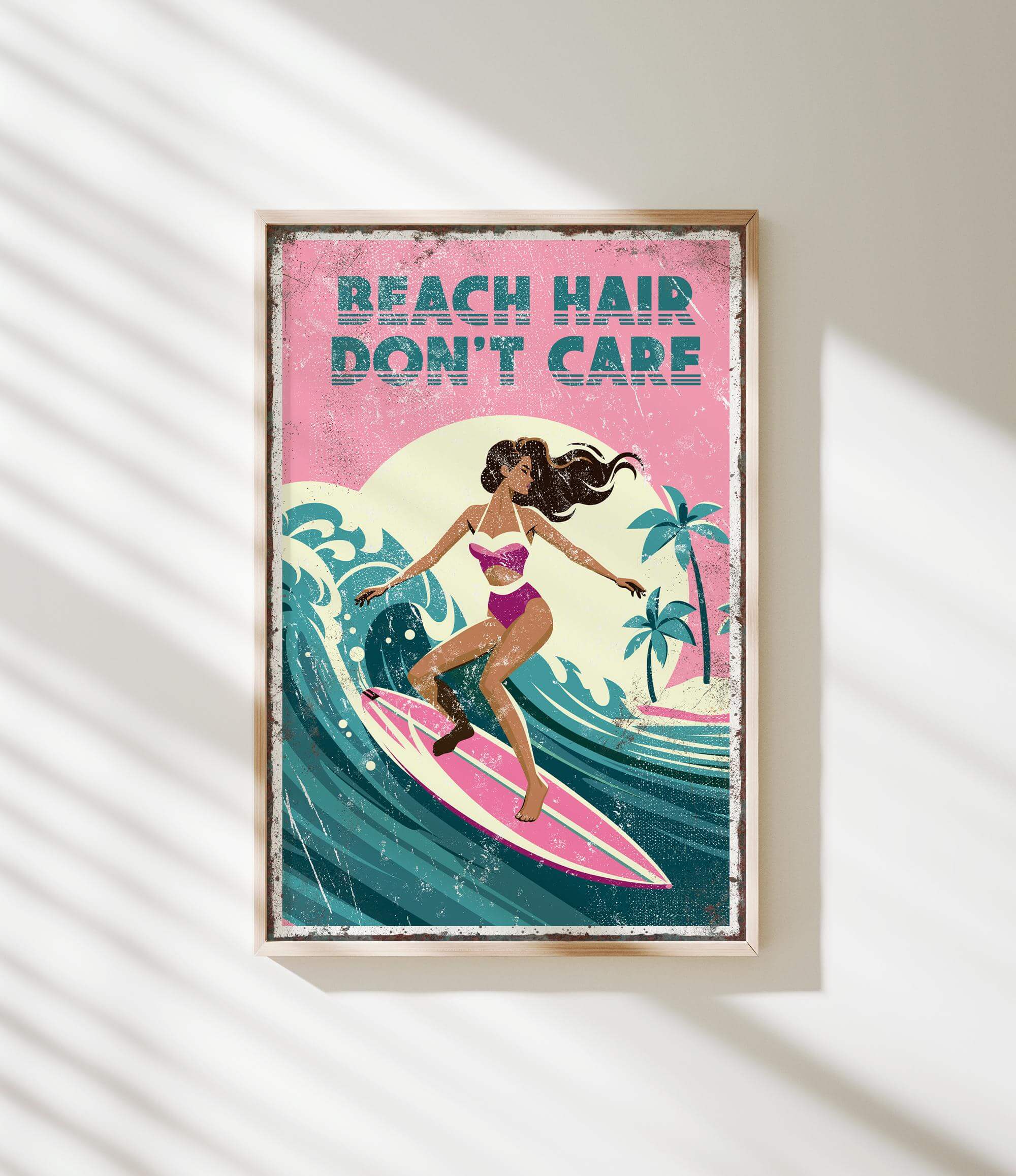 A framed poster with a woman surfing on a pink surfboard, with the text "REACH HAIR DON'T CARE" written above her.