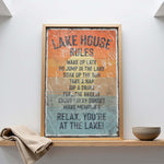 A framed sign with a list of rules for a lake house, including activities such as waking up late, jumping in the lake, taking a nap, drinking, taking a nap, drinking, feeling the breeze, enjoying the sunset, and making memories.