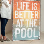 a woman standing next to a sign that says life is better at the pool