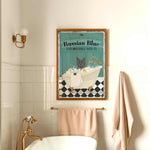 a bathroom with a framed poster of a cat in a bathtub, a white bathtub, and a towel rack.