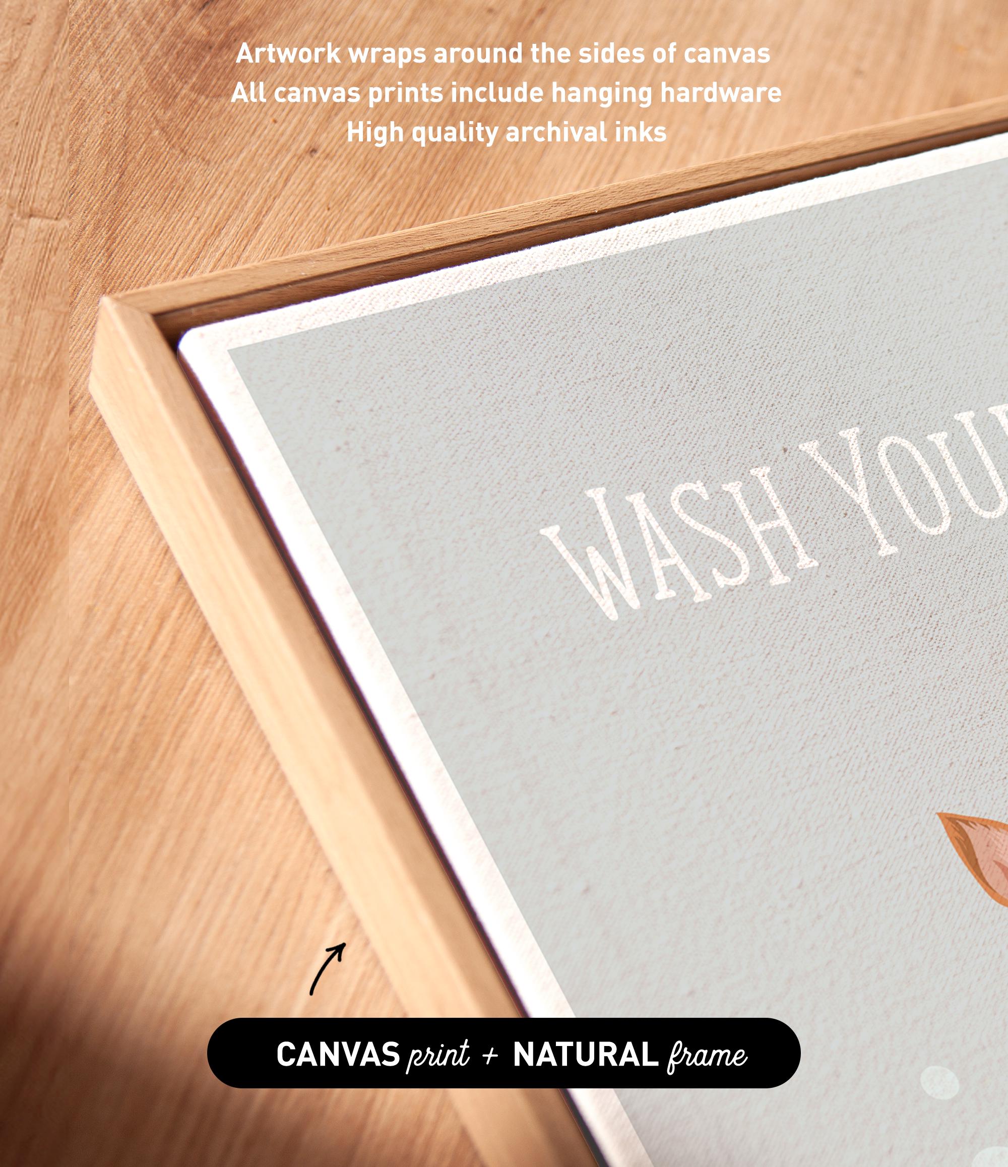 a close-up view of a canvas print with the text "WASH YOURS" prominently displayed on it. The print is framed in a natural frame, and the text indicates that the artwork wraps around the sides of the canvas, and all canvas prints include hanging hardware for high quality archival inks.