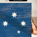 a hand holding a piece of wood with white stars painted on it