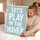 a woman holding a sign that says let&#39;s play in the waves