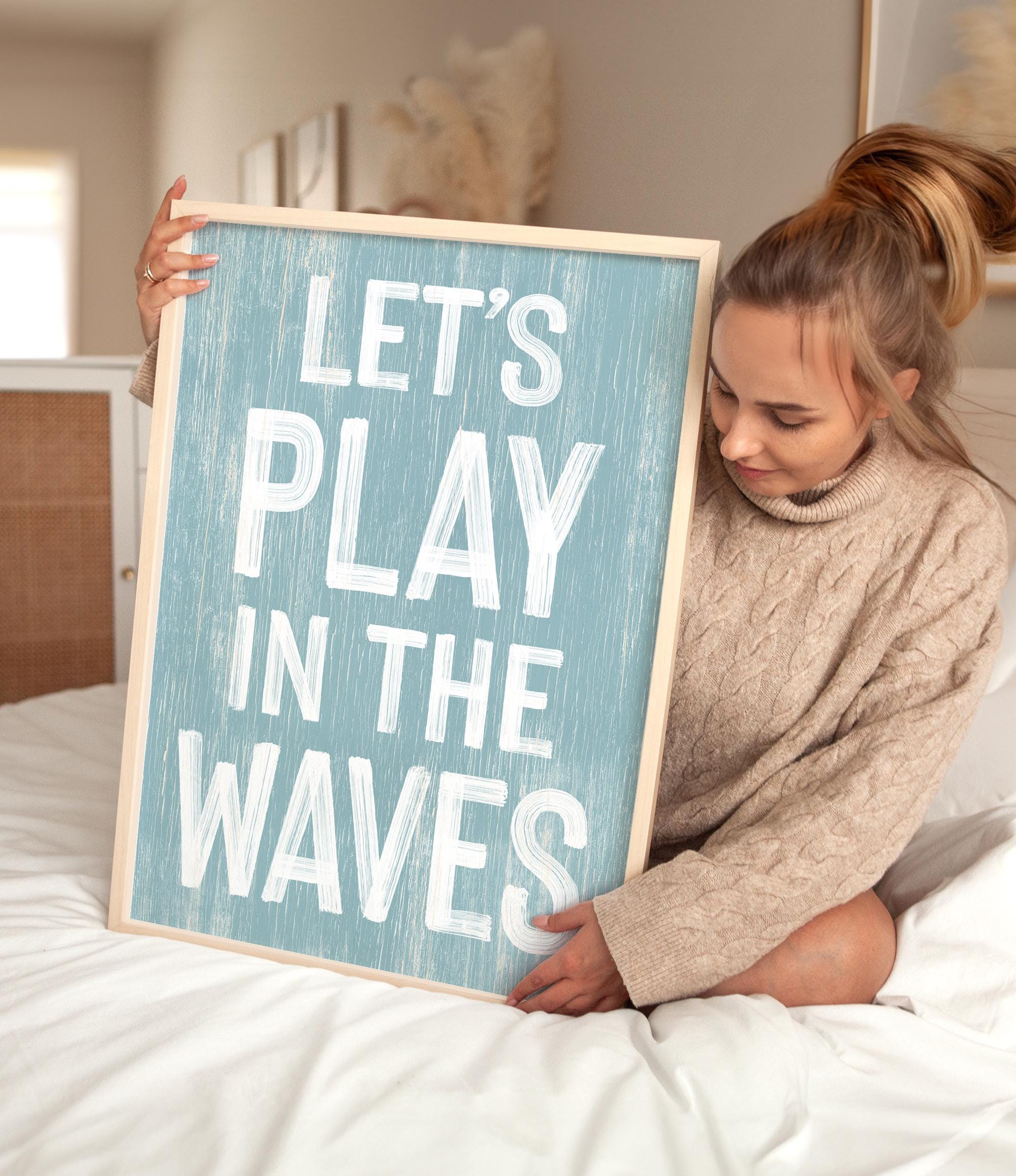 a woman holding a sign that says let&#39;s play in the waves