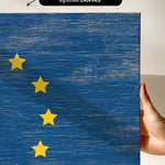 a hand holding a piece of wood with a flag painted on it