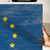 a hand holding a piece of wood with a flag painted on it
