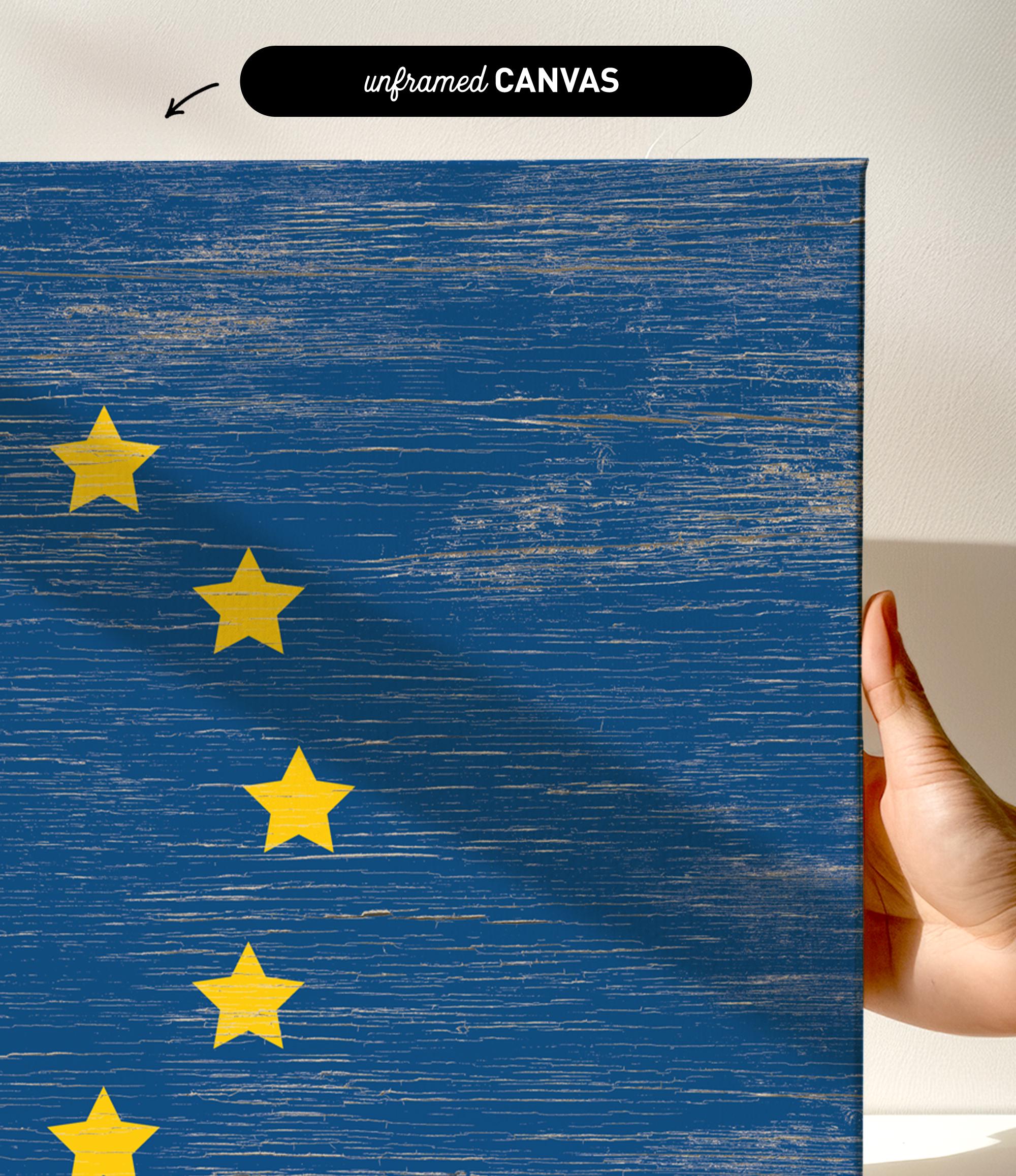 a hand holding a piece of wood with a flag painted on it