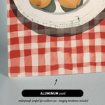 The image is an aluminum print depicting a plate with fruit on a red and white checkered tablecloth.