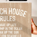 a hand holding a canvas print with the text "CHEACH HOUSE RULES" written on it.