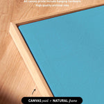 a close-up view of a blue canvas with a wooden frame, highlighting the artwork wrapping around the sides of the canvas and the high-quality archival inks used for the print.