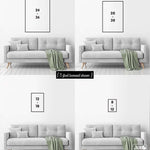 Four sizes of the PIPE DOWN, Sailboat Sunset Sign vintage wall art are displayed above a gray loveseat with a green blanket in a modern white room.